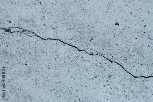 A close-up view of a concrete surface shows a noticeable crack running through it, revealing the effects of weathering and wear in an urban area during daytime