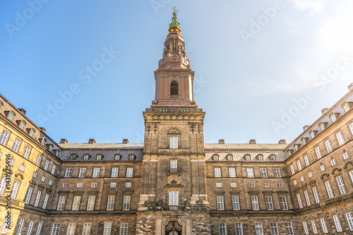 Tableau sur toile Visitors admire the stunning architecture of Christiansborg Palace in Copenhagen, surrounded by historical charm under a bright blue sky