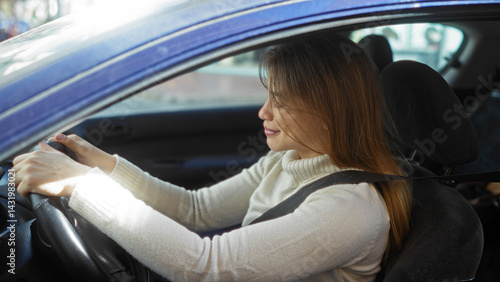 Obraz na płótnie Woman driving car in urban city street showing concentration and focus while enjoying the outdoor experience in a modern vehicle during daytime travel. w salonie
