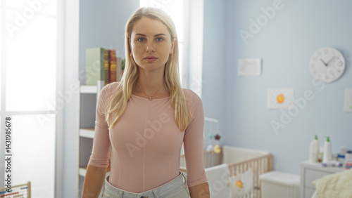 Obraz na płótnie Woman standing indoors in a cozy bright bedroom looking serene in a casual outfit, surrounded by baby furniture, books, and decor, basking in natural light. w salonie