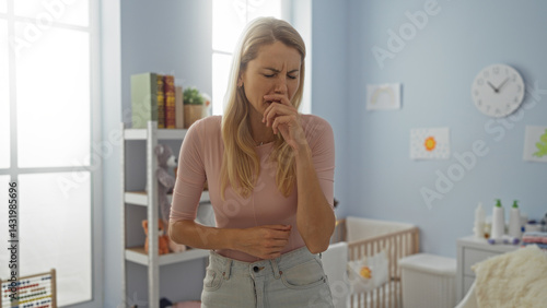 Woman coughing in a well-lit bedroom with a crib, illustrating health concerns and indoor living environment, emphasizing her young and attractive appearance.
