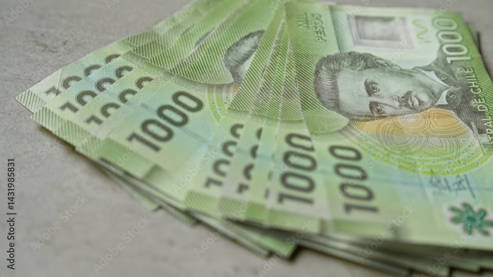 Chilean banknotes of 1000 pesos stacked on a concrete surface highlighting the currency intricacies.