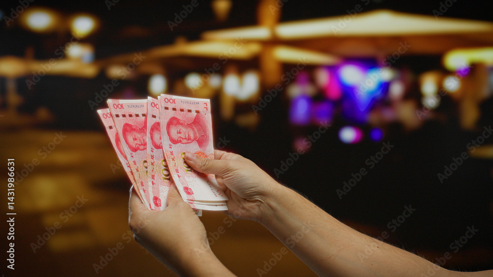 Man holding chinese yuan banknotes on an urban street highlighting business and financial themes in an outdoor city environment.