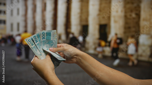Man holding brazilian real banknotes on a bustling city street, capturing a vibrant urban business scene with a focus on currency and commerce.