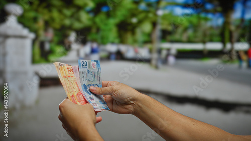 Man holding mexican banknotes outdoors in an urban street suggesting business or investment opportunity in a vibrant city setting underlining financial prospects.