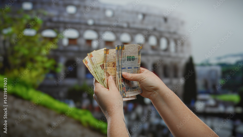 Woman displaying peruvian soles in front of the roman coliseum, symbolizing a blend of cultures with currency exchange in an urban outdoor setting.