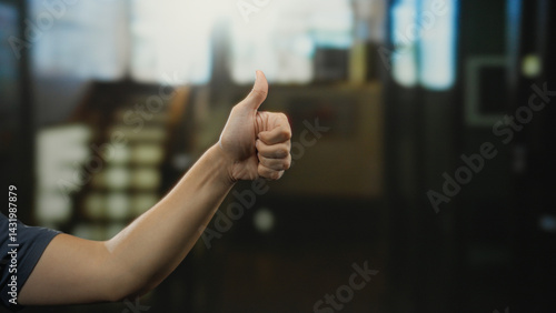 Obraz na płótnie Man's hand giving thumbs-up indoors at a hotel reception with a blurred background indicating a positive and welcoming environment for guests and travelers. w salonie