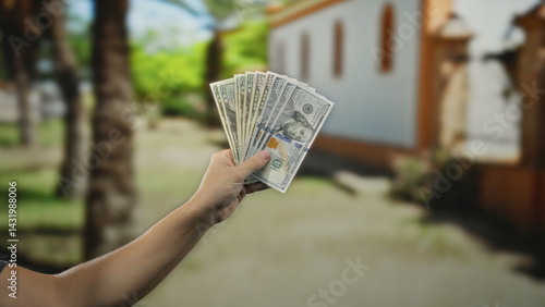 Obraz na płótnie Man holding american dollars on a city street, showcasing financial success with a cityscape backdrop, bright day and urban setting, emphasizing wealth and opportunity. w salonie