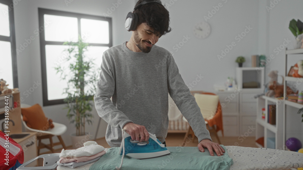 Young man ironing clothes in a bright laundry room while wearing headphones, creating a peaceful and efficient home cleaning experience.