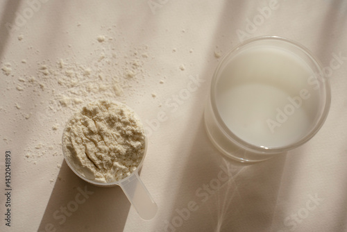 Whey protein powder in measuring scoop and glass on tale in bright sunlight