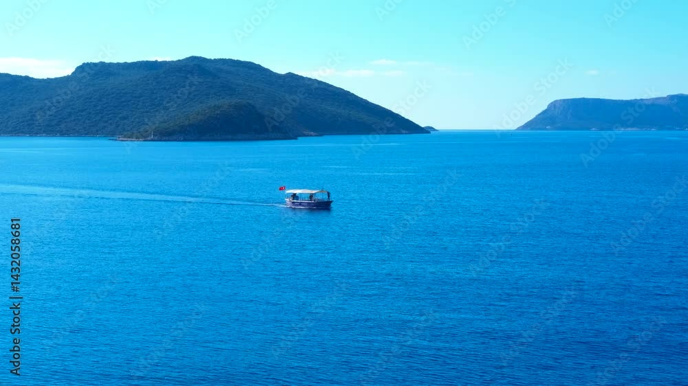 Passenger ferry gliding smoothly across serene blue waters, passing verdant island coastline under bright sunlight, generating gentle wake during scenic maritime journey Passenger ferry gliding smoothly across serene blue waters, passing verdant island coastline under bright sunlight, generating gentle wake during scenic maritime journey