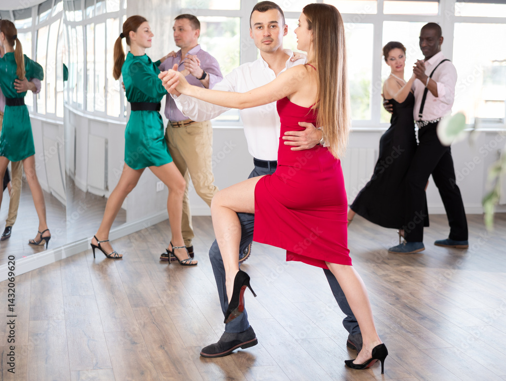 Fototapeta premium Positive young man and woman practicing waltz in pair in dancing studio