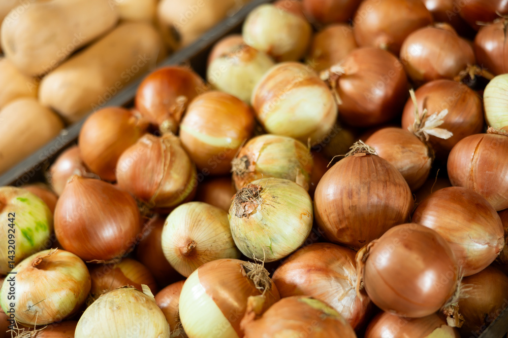 A lot of golden common onions placed in wooden box in open-air vegetable market A lot of golden common onions placed in wooden box in open-air vegetable market