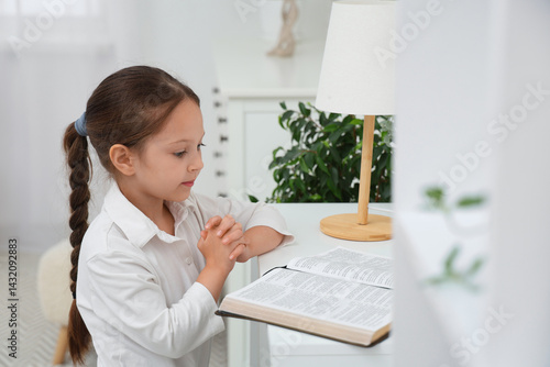 Cute little girl reading Bi...
