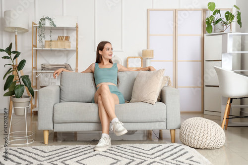 Young woman sitting on grey...