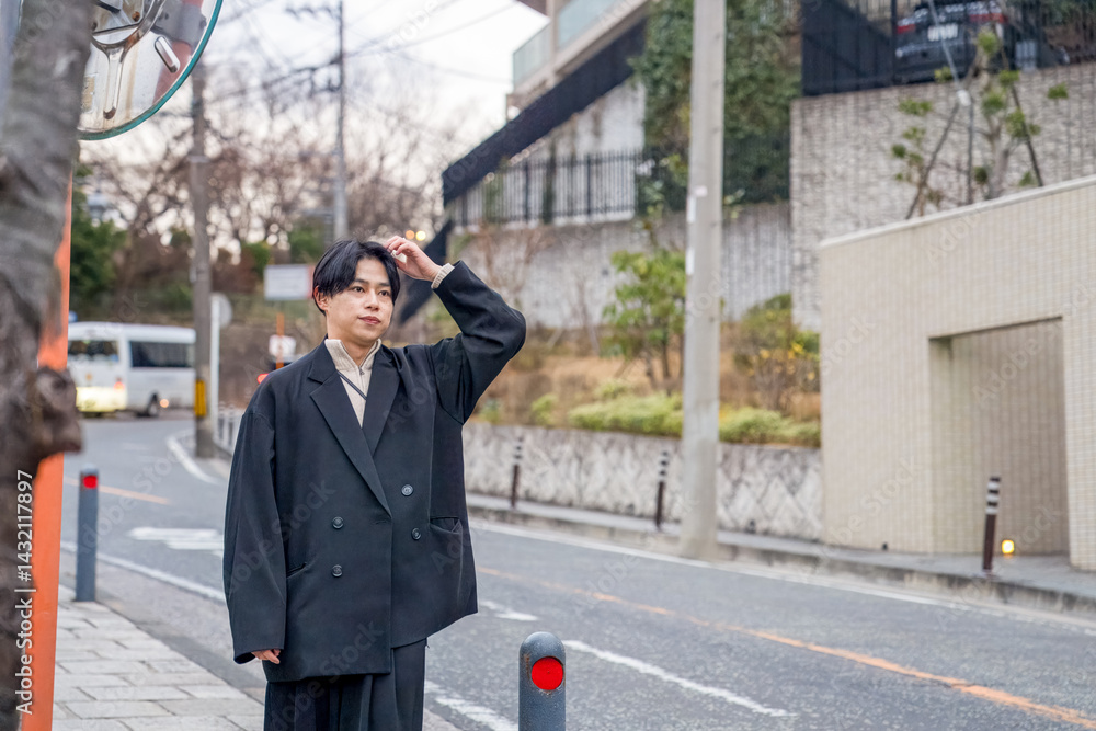 A Japanese man in his twenties wearing a black jacket is in Minato Mirai, Yokohama, Kanagawa Prefecture. He walks through the city in the evening, surrounded by warm lights and gentle sunset glow.