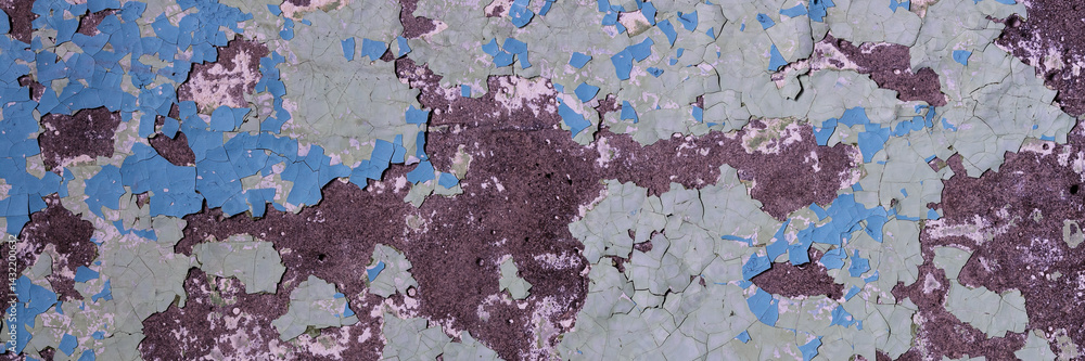 Peeling paint on the wall. Panorama of a concrete wall with old cracked flaking paint. Weathered rough painted surface with patterns of cracks and peeling. Panoramic texture for background and design.