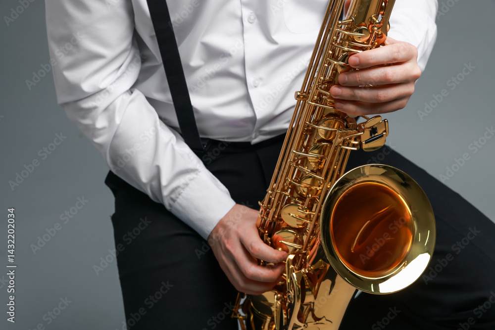 Naklejka premium Professional musician playing saxophone on grey background, closeup