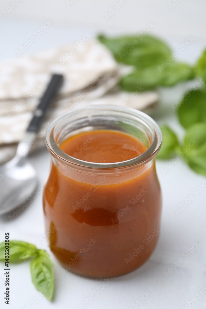 Tasty curry sauce in glass jar and basil on white tiled table, closeup Tasty curry sauce in glass jar and basil on white tiled table, closeup