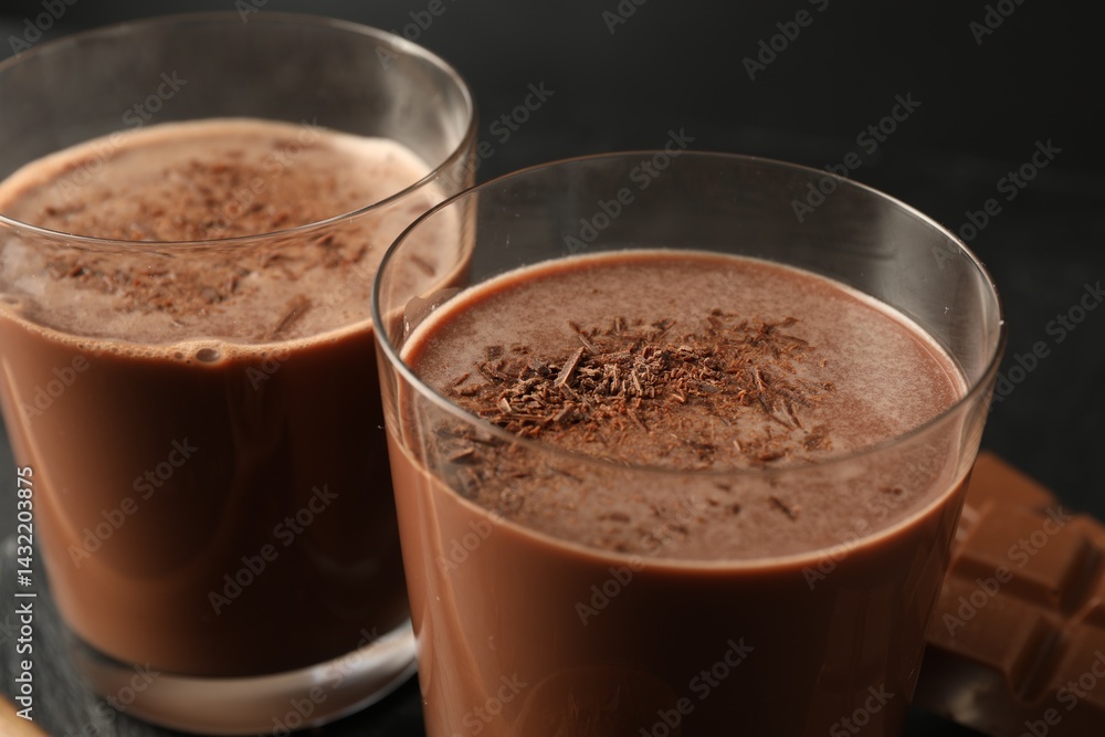 Tasty chocolate milk with shavings on black table, closeup Tasty chocolate milk with shavings on black table, closeup