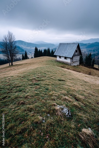 Isolated cabin on a hilltop with a foggy landscape and distant mountains in the background