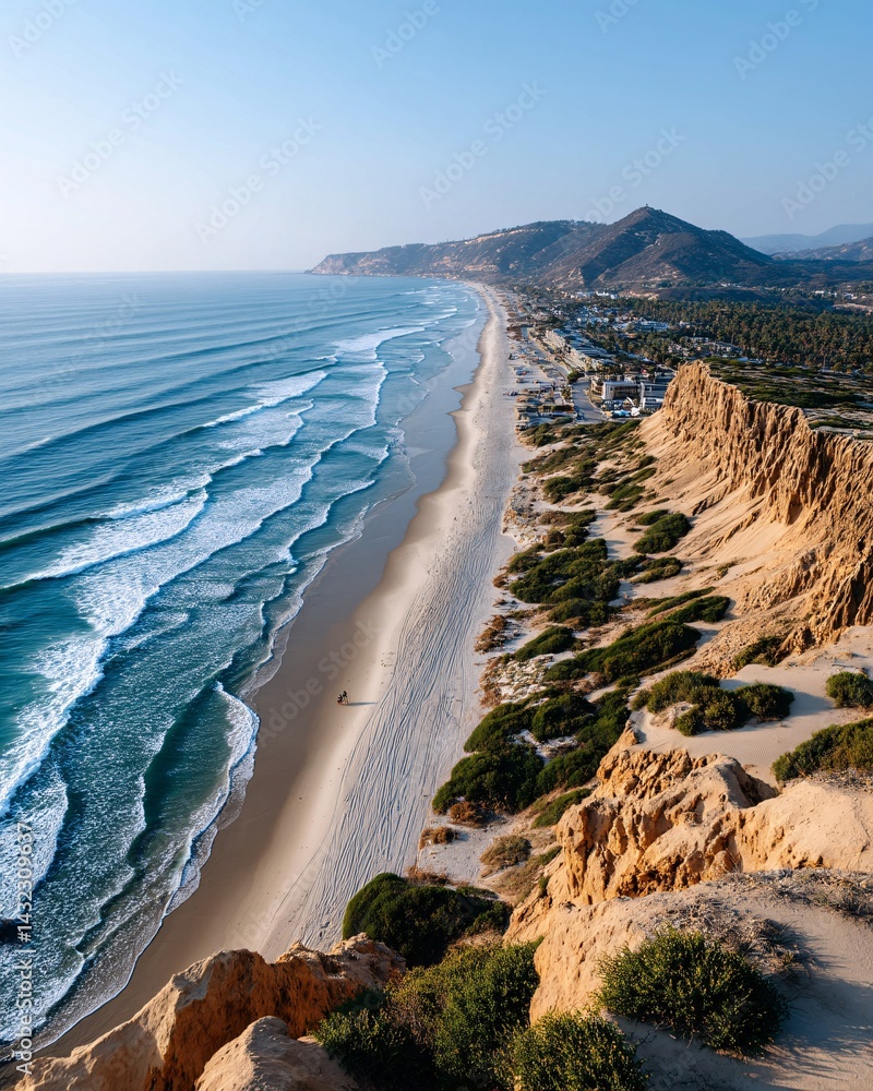 Serene Coastal View with Gentle Waves and Rocky Cliffs under Clear Blue Sky