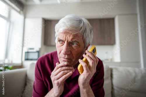 Tired distrust shocked retiree man in discomfort listening to unknown caller making dubious requests. Phone scam warning call, social engineering, elder fraud, telemarketing, call manipulation