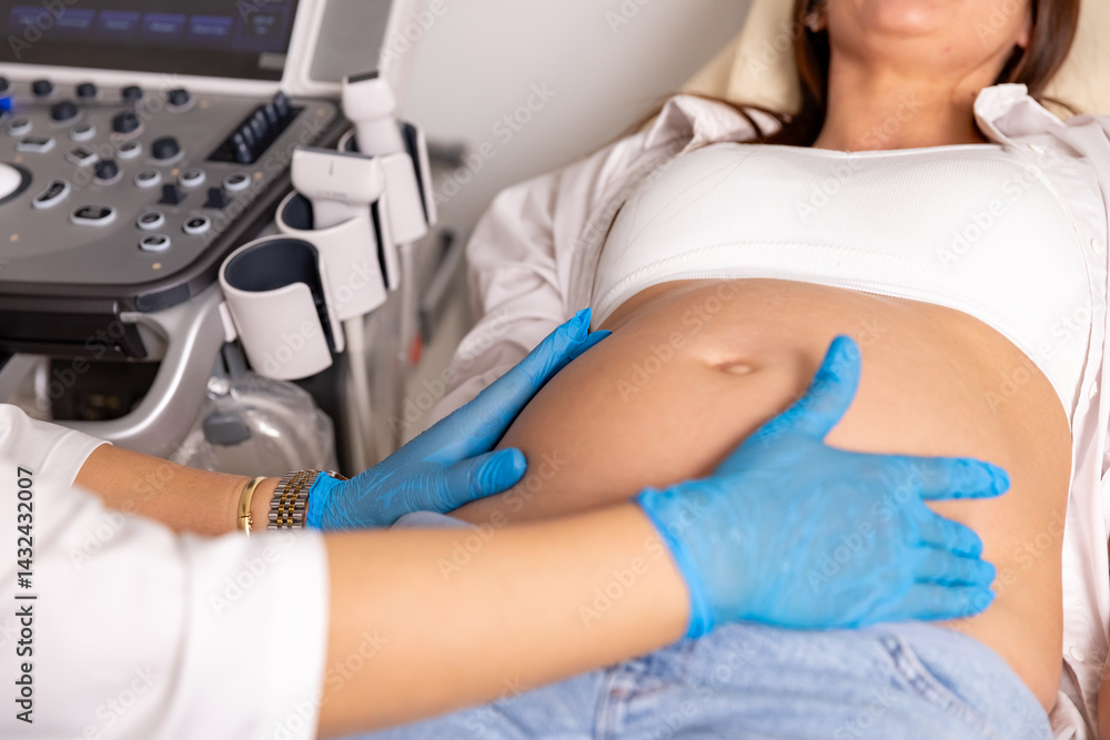 Close up shot of female doctor examining pregnant woman lying on bed in clinic. Palpation of womb belly, feeling baby fetus embryo bumps. Gynecologist checkup