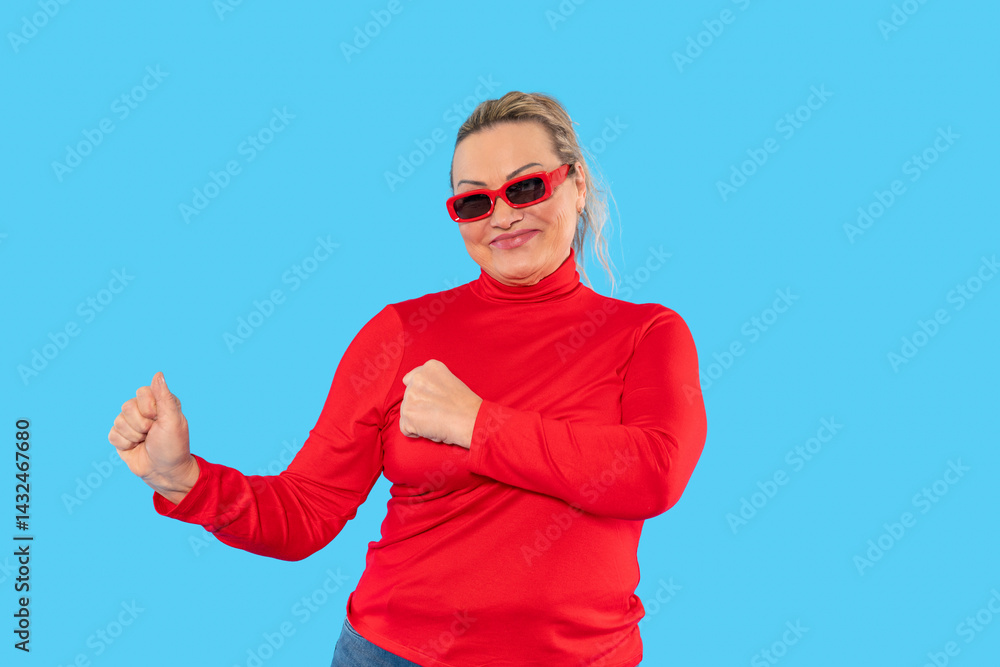 Naklejka premium Woman in red sweater dancing playfully against a bright blue background during a cheerful moment in a lively indoor setting