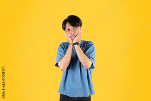 Valokuva Young Asian man in a blue t-shirt against a yellow background, gesture of hand r