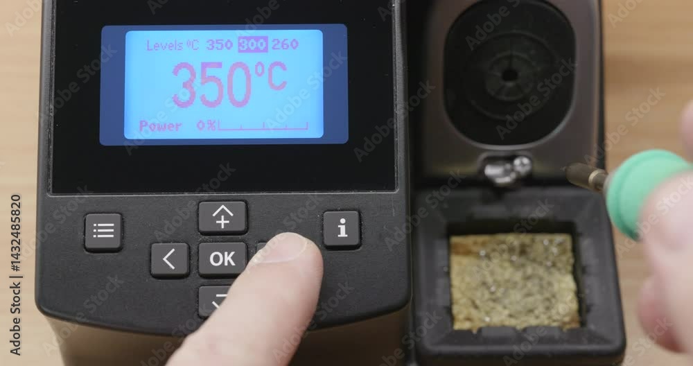 Engineer adjusting soldering temperature and cleaning tip Engineer adjusting soldering temperature and cleaning tip
