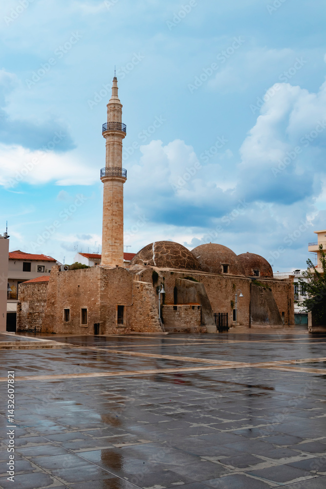 A captivating view of a historic mosque featuring a tall minaret in Rethymno, Greece, against a cloudy sky. Crete island.