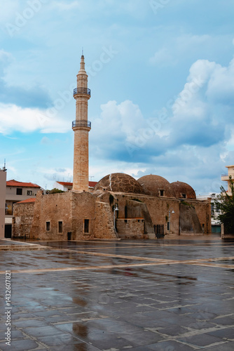 A captivating view of a historic mosque featuring a tall minaret in Rethymno, Greece, against a cloudy sky. Crete island.