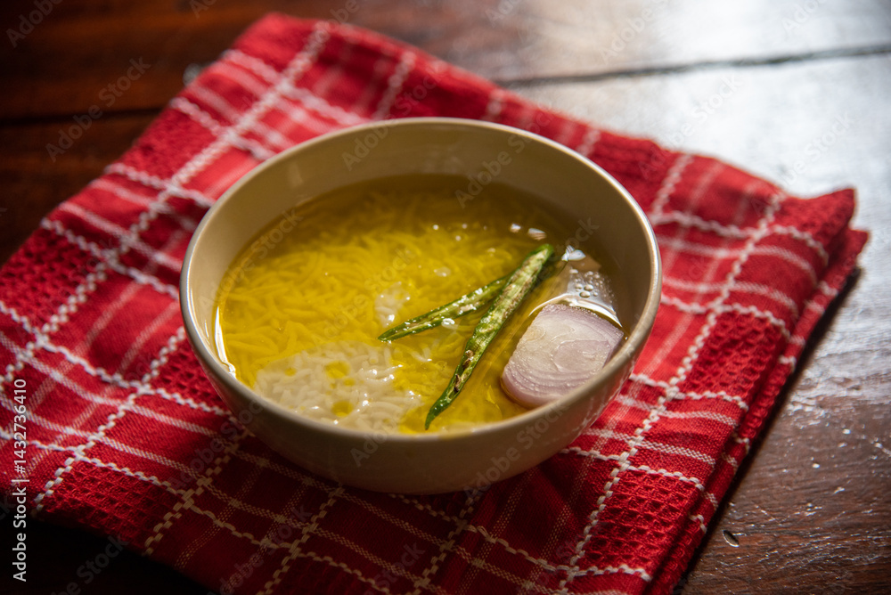 Panta bhat or pakhala or fermented rice soup with water, green chillies and onion in a bowl. Staple food in Eastern India. Close up, selective focus.