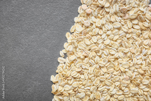 Close up photo of organic oat flakes on a dark slate background.
