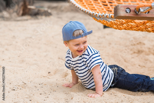 Summer lifestyle. A cute little boy is having fun playing in a hammock on the beach on a modern playground. The concept of family entertainment and leisure.