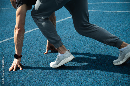 Obraz na płótnie Close up of side view of mans feet in sport shoes running on blue running track. Start. Season workout, crossfit and training. w salonie