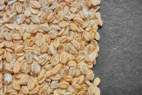 Close up photo of organic rye flakes on a dark slate background, selective focus.