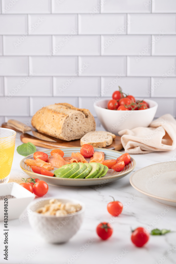 Marble table with a plate of avocado and cherry tomatoes. Background with whole grain bread, tomato bowl, and soft cloth. Fresh and balanced composition. Concept of healthy food and natural lifestyle Marble table with a plate of avocado and cherry tomatoes. Background with whole grain bread, tomato bowl, and soft cloth. Fresh and balanced composition. Concept of healthy food and natural lifestyle