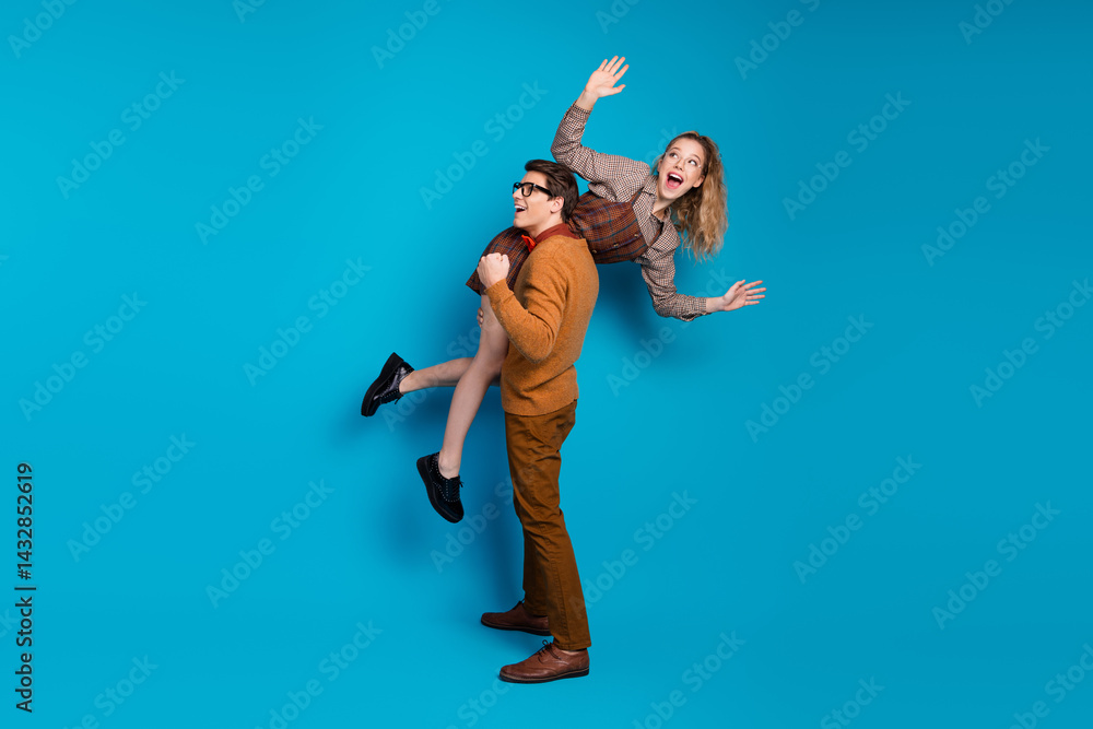 Playful couple in vintage attire having fun on a vibrant blue background