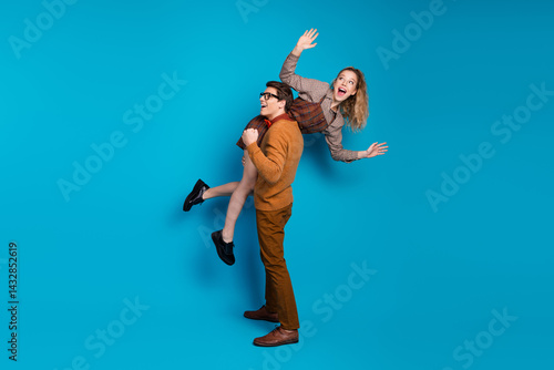 Obraz na płótnie Playful couple in vintage attire having fun on a vibrant blue background w salonie