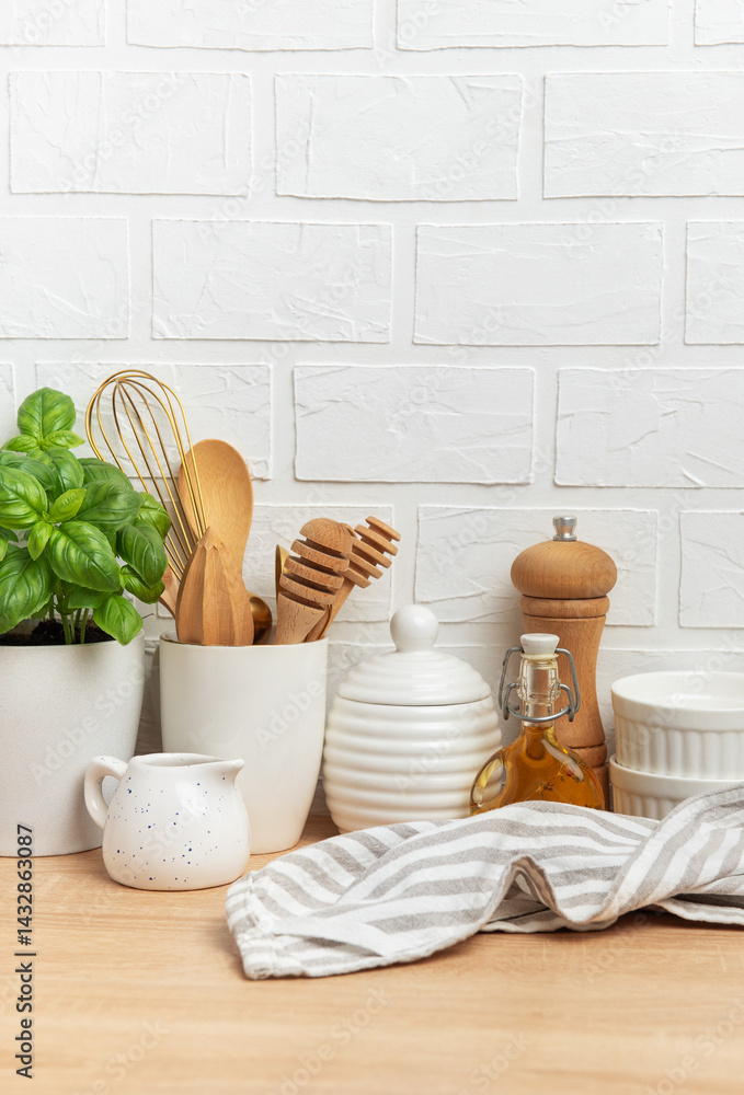 Kitchen utensils, basil plant and linen napkin creating cozy atmosphere on table