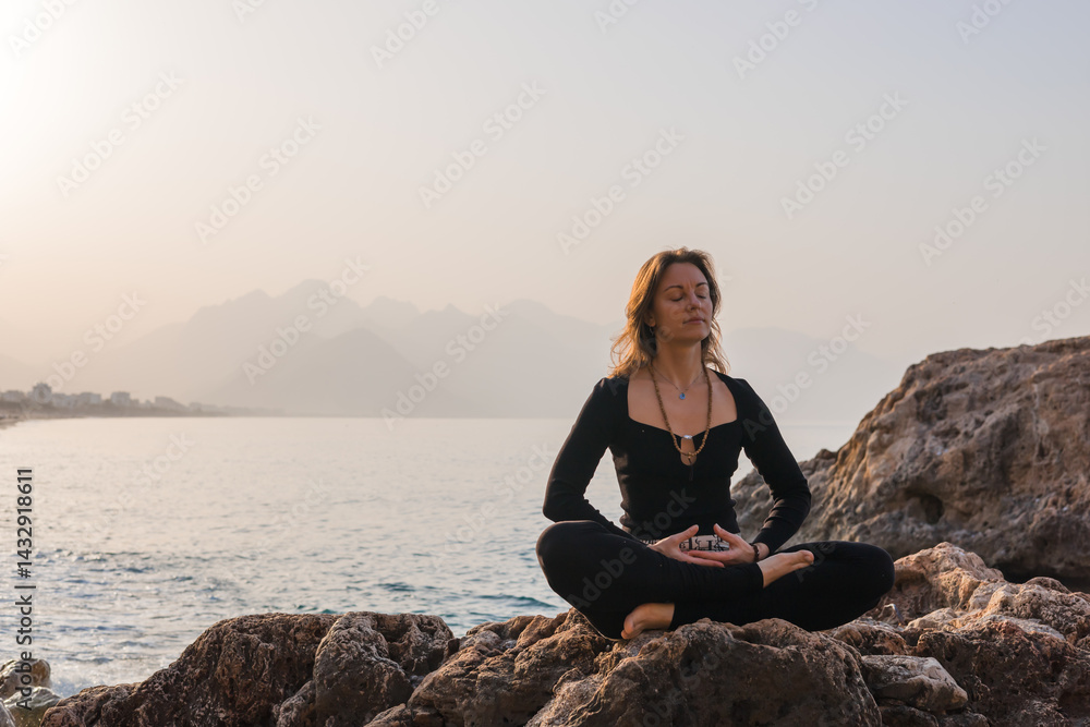 Practicing yoga on rocky beach at sunrise for relaxation and mindfulness Practicing yoga on rocky beach at sunrise for relaxation and mindfulness