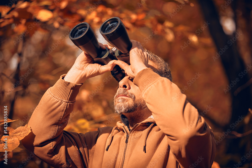 Amateur birdwatcher observing birds and other animals in nature with binoculars.