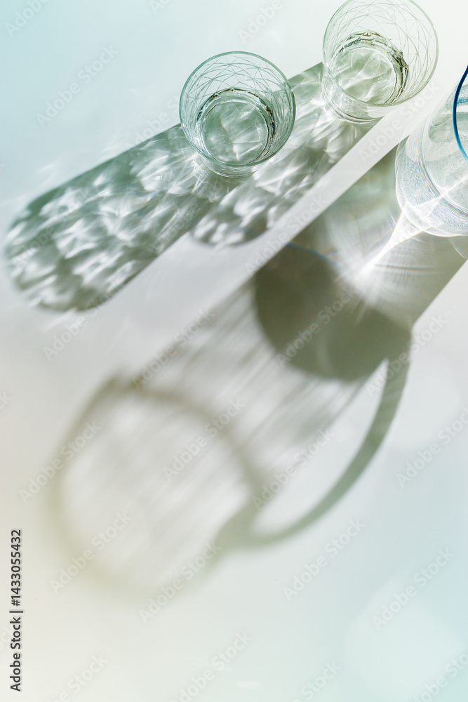 Water Glasses and water jug with Shadows and sunlight Reflection on white background, colored photo minimal style, aesthetic summer still life, refraction throug crystal shine cups, caustics