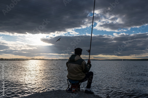 A fisherman catches fish at the Verkh-Isetskoye reservoir at sunset on a summer evening, Yekaterinburg