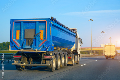 Bild auf Leinwand Truck huge blue dump trailer heavy bulk cargo drives fast along the highway, rea
