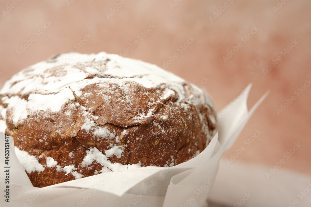 Traditional Easter cake with powdered sugar on soft beige linen background. Rustic homemade dessert for spring holiday