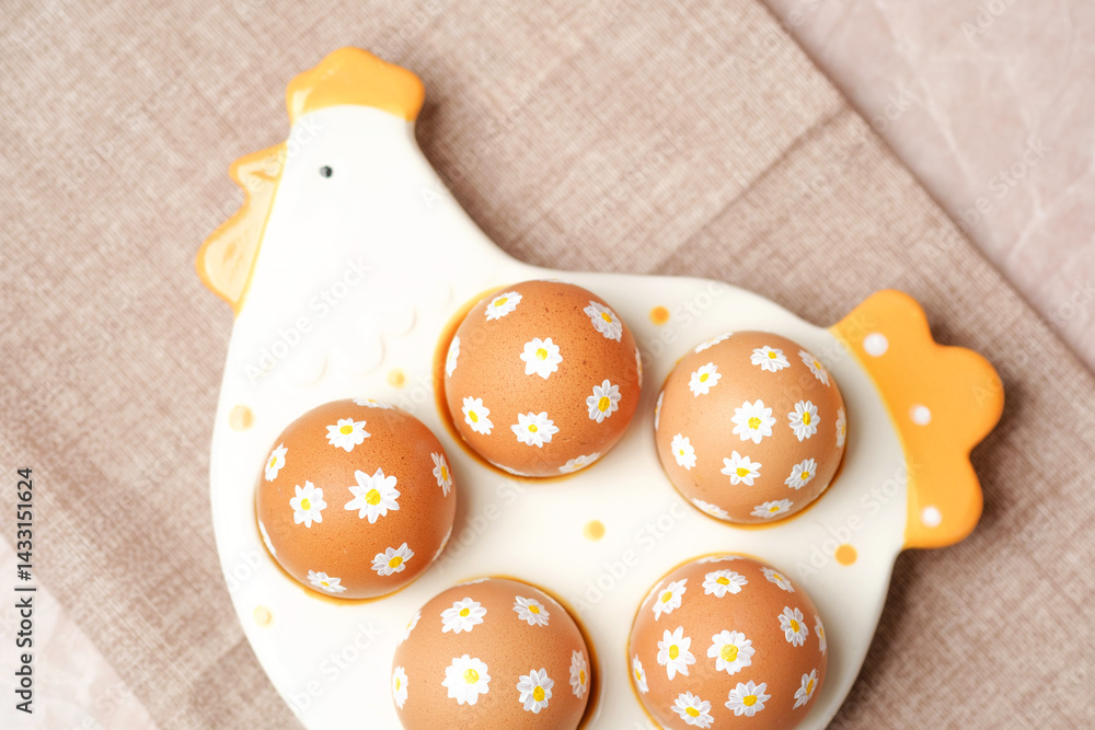 Easter eggs with white daisy flowers on ceramic chicken tray.