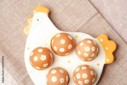 Obraz na płótnie Easter eggs with white daisy flowers on ceramic chicken tray. w salonie